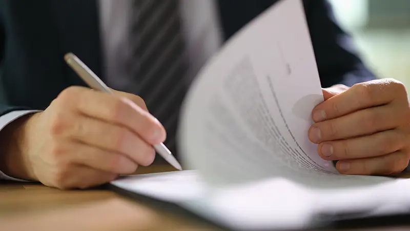 Les armes à la disposition de la caution 1 Main d’un dirigeant signant un contrat de cautionnement bancaire sur une table de bureau