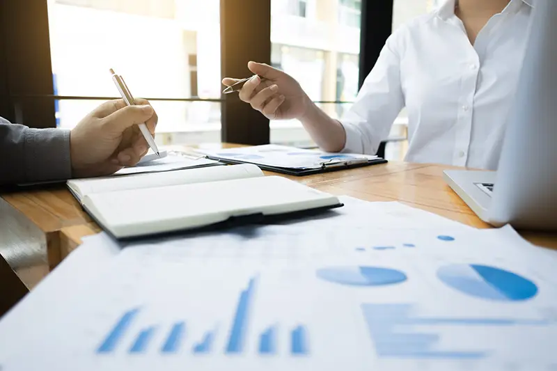 Un candidat à la franchise et un professionnel examinent des documents financiers et des statistiques pour sécuriser le projet et aller au-delà des exigences minimales du DIP imposées par la loi Doubin.